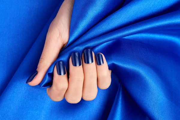 Uma Mão Feminina Com Unhas Azuis Segurando Tecido Cetim Azul — Fotografia de Stock