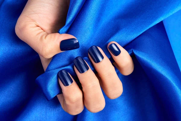 Uma Mão Feminina Com Unhas Azuis Segurando Tecido Cetim Azul — Fotografia de Stock