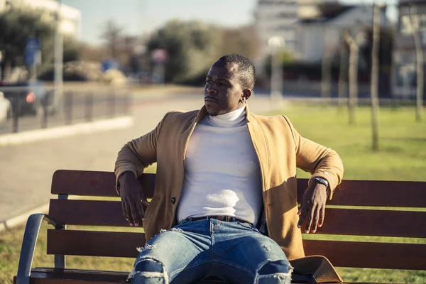 ベンチに座ってコートにスタイリッシュなハンサムなアフリカの男性の選択的なフォーカスショット — ストック写真