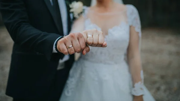 花嫁と新郎の拳のクローズアップショットは 彼らの結婚指輪を示す — ストック写真