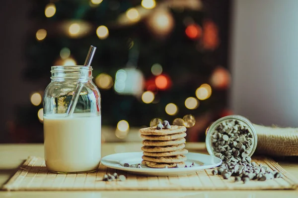 Die Schokoladenkekse Und Ein Glas Milch Mit Weihnachtsbaum Hintergrund — Stockfoto