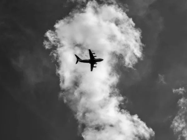 在蓬松的云雾中飞行的飞机的灰度照片 — 图库照片