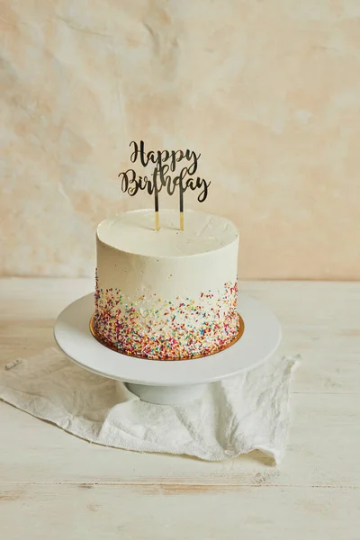 幸せな誕生日 ケーキトッパーとテーブルの上のトレイにスプリンクルケーキの垂直ショット — ストック写真
