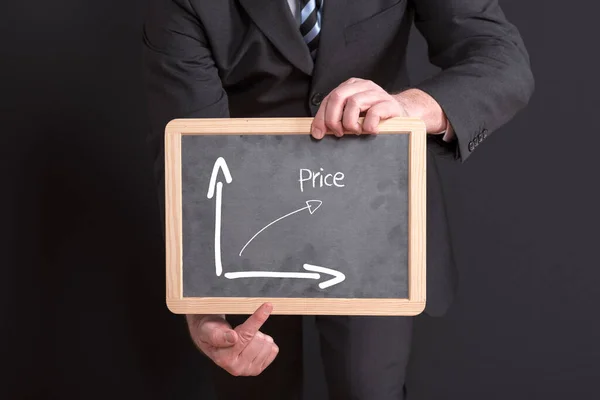 黒の背景を背景に価格グラフが成長している黒板を持つビジネスマン — ストック写真