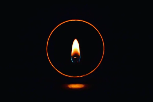 A long exposure fire ring around the burning candle flame glowing in the darkness
