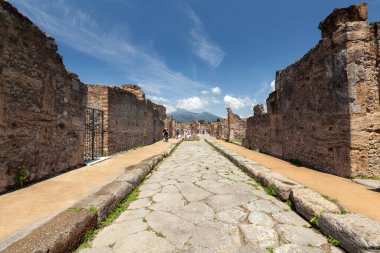 POMPEI, ITALY - Jan 28, 2021: A cobblestone street in Pompei with Mount Vesuvius in the background clipart