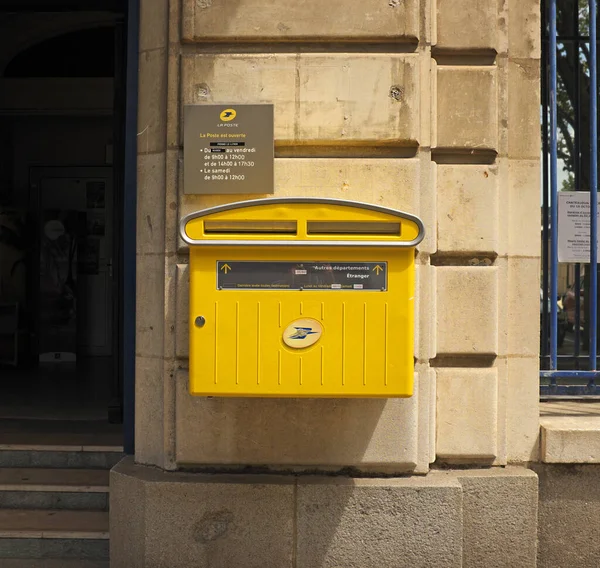 CHATEAUDUN, FRANCE - Sep 03, 2017: Yellow French mail box fixed to outside wall of a post office, next to entrance. Also visible is sign showing opening hours of post office.