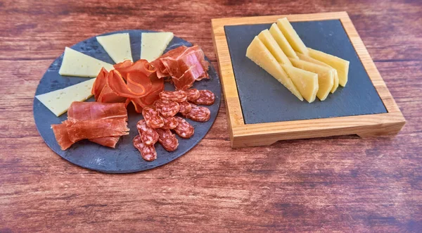 木製のテーブルの上にソーセージとチーズのトレイ — ストック写真