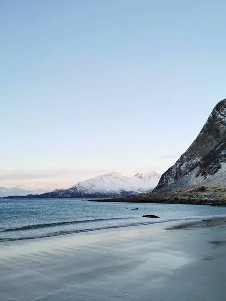 ノルウェー トロムソ州クヴァルーヤの海岸にある雪の山の垂直ショット — ストック写真