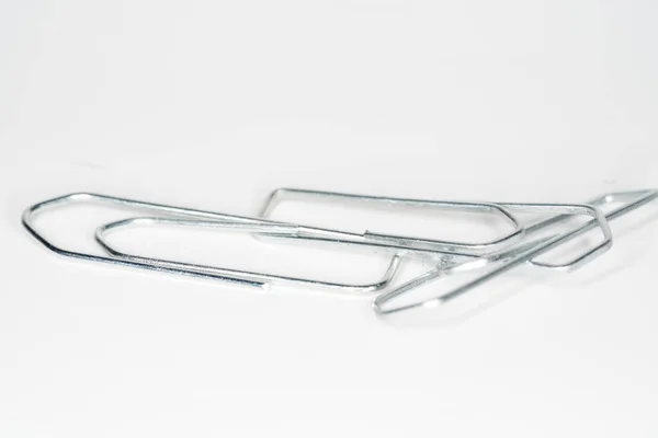 Eine Nahaufnahme Von Drei Silbernen Büroklammern Auf Einer Weißen Oberfläche — Stockfoto