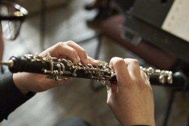 A closeup of a person playing the oboe, indoors clipart