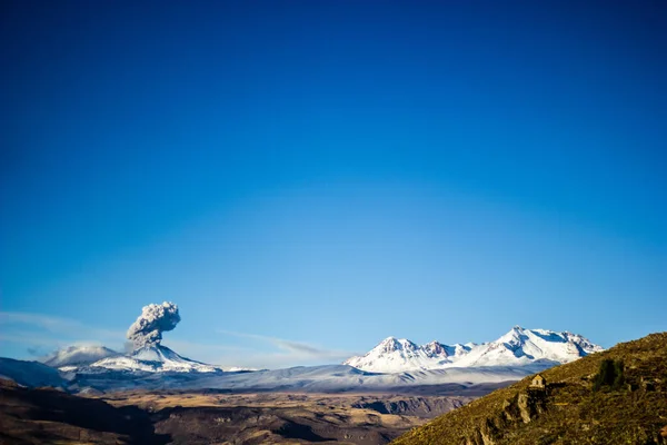 空気中の煙やほこりで噴火中の雪の山の範囲の高山風景 — ストック写真