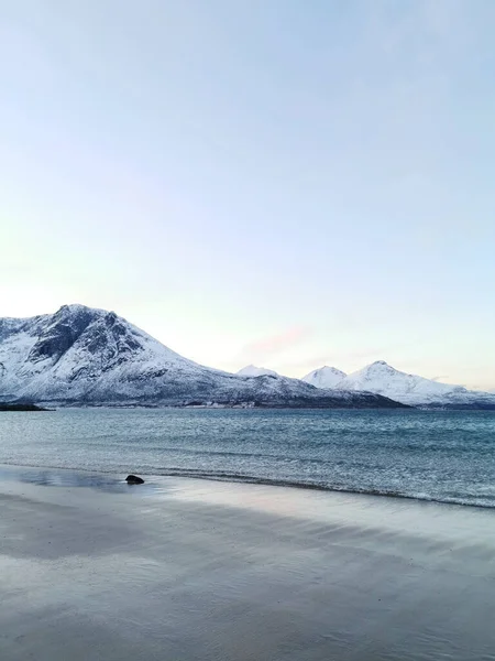 ノルウェー トロムソ州クヴァルーヤの海岸にある雪の山の垂直ショット — ストック写真