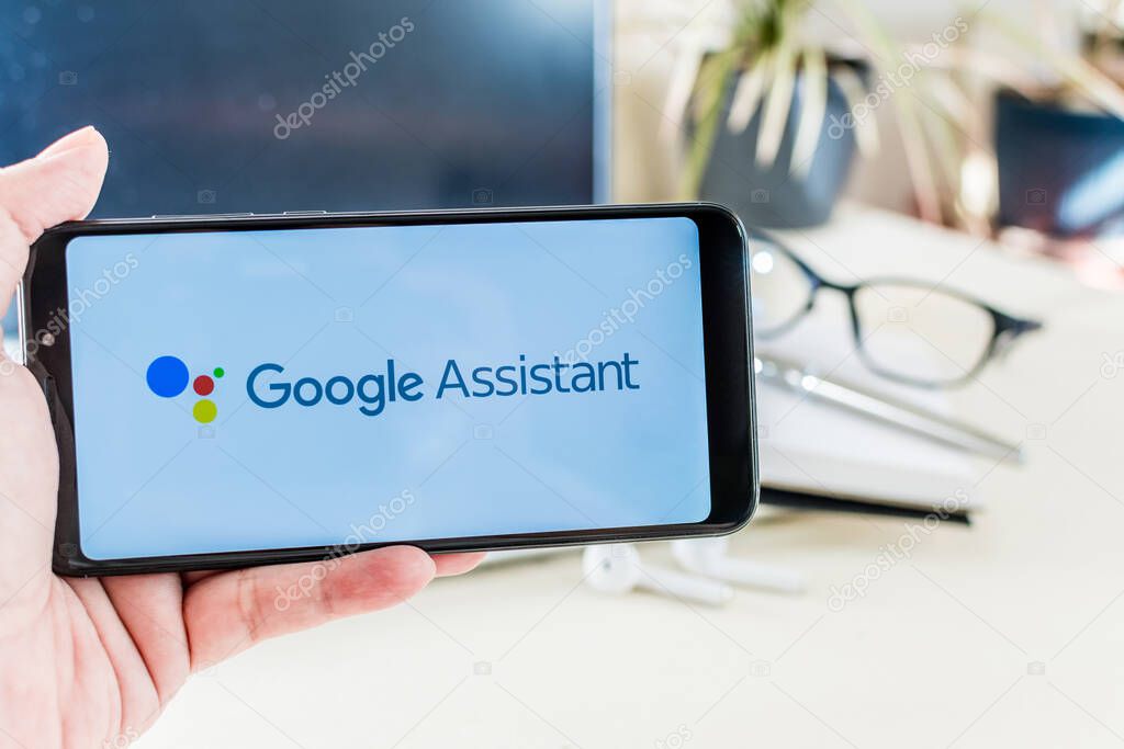 BEER SHEVA, ISRAEL - Dec 29, 2020: Beer Sheva, Israel. December 29, 2020: Hand holding a mobile with Google Assistant logo on screen, on desk. Google Assistant.