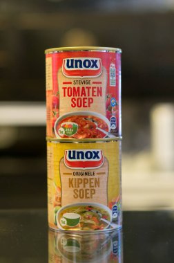AMSTERDAM, NETHERLANDS - Jan 02, 2017: Unox chicken and tomato soup in cans on a table clipart