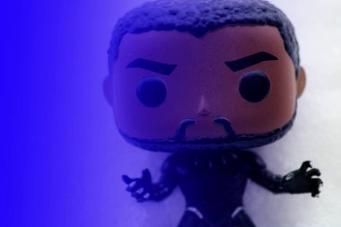 CHELMSFORD, UNITED KINGDOM - Feb 07, 2021: Black panther Funko POP with a blue glow. on a bed of snow clipart