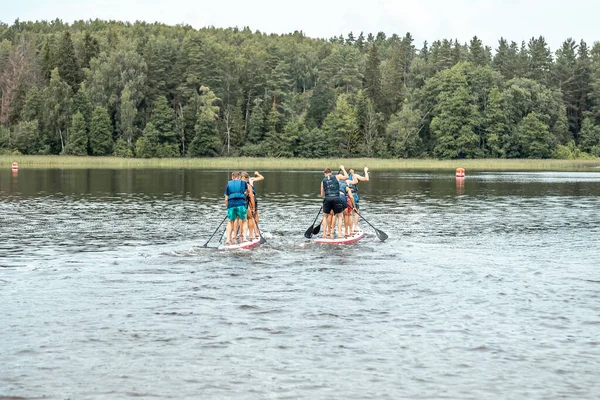 A Stand up paddle SUP race competition. People rowing with Dragon boards in SUP festival.
