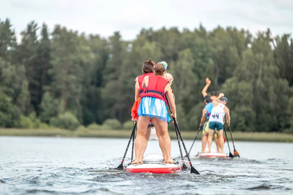 A Stand up paddle SUP race competition. People rowing with Dragon boards in SUP festival.