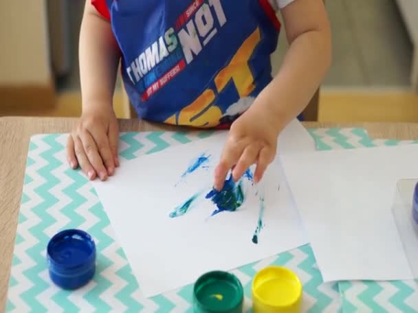 年轻的波兰白人男孩在家中的一张木制桌子旁 用手指和水彩画着空白的纸 — 图库视频影像