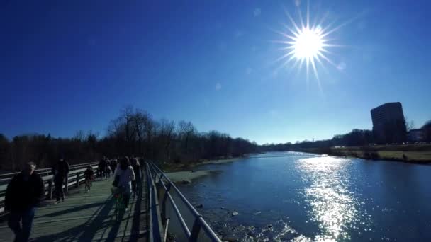 人々はミュンヘンのThalkirchenで冬の終わりに良い天気をお楽しみください 川沿いの公園には多くのウォーカーや自転車が走っています — ストック動画