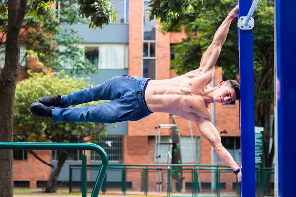 A hot young muscular man working out on horizontal bars