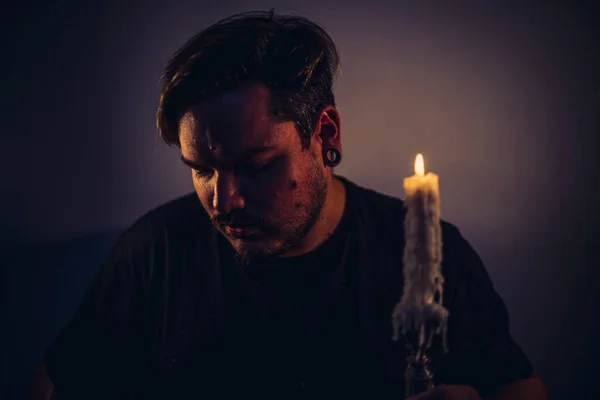 在黑暗的房间里拿着燃烧着的蜡烛的有胡子和耳孔的男性画像 — 图库照片