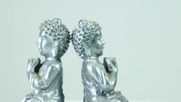 Closeup Two Silver Buddha Statues Spinning Back Back Front White — Stockvideo