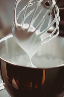 A closeup vertical shot of a whisk mixing egg whites for cream in a bowl clipart