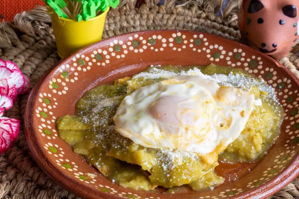 Mexican food. Green chilaquiles with over medium eggs, with sour cream and cheese