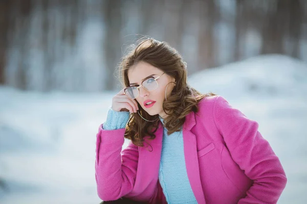 魅力的なブルネット女性で眼鏡とかわいいピンクのコートポーズのためにカメラのために冬の日 — ストック写真