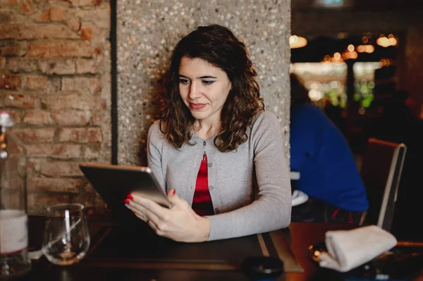 一个坐在餐馆里用平板电脑的年轻女性的肤浅的焦点 — 图库照片