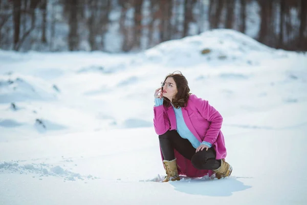 ピンクのコートを着て雪の中でポーズをとるスタイリッシュな女性 — ストック写真