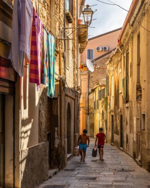 NICOTERA, ITALY - Aug 18, 2020: Nicotera, Calabria, Italy, Aug. 20  Two boys walking in a typical narrow alley of Nicotera old town  clipart
