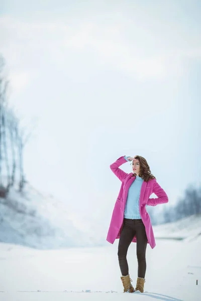 額に手で遠くを見てピンクのコートの女性の垂直ショット — ストック写真
