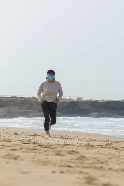 해변에서 외과용 마스크를 초점이 곳에서 달리고 있습니다 — 스톡 사진