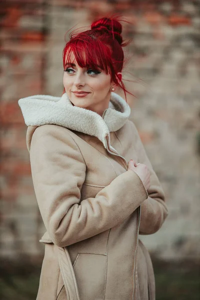 一位年轻美丽的红头发女人 留着刘海 穿着一件温暖的冬衣 背景模糊 头戴头巾 面带微笑 — 图库照片