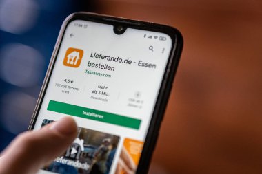BERLIN, GERMANY - Mar 13, 2021: The Lieferando.de mobile App is opened in the play store on a smartphone. The food delivery App was used frequently during the covid pandemic. clipart