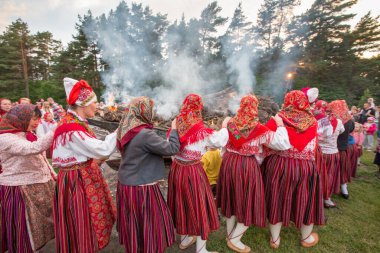 KIHNU ISLAND, PRNU COUNTY, ESTONIA, EUROPE, ESTONIA - Jun 23, 2013: Women's  in Kihnu isl costumes performing ritual dance and song for celebrating the summer  solstice and to respect fishing boat set on fire   clipart