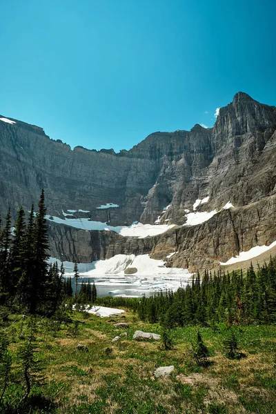 A vertical shot of snowy mountains under a clear blue sky