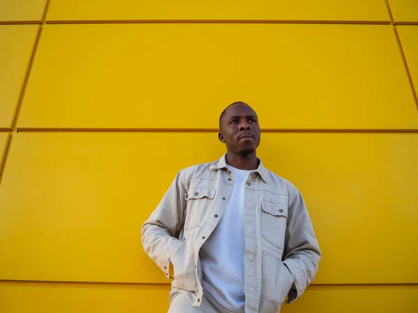 黄色の壁に向かってポーズをとるファッショナブルな黒人スペイン人男性 — ストック写真