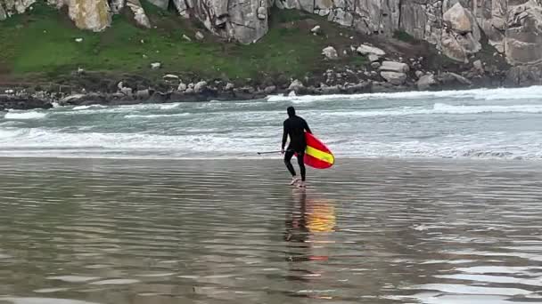 Video Surfista Caminando Por Playa Llevando Colorida Tabla Surf Roja — Vídeo de stock