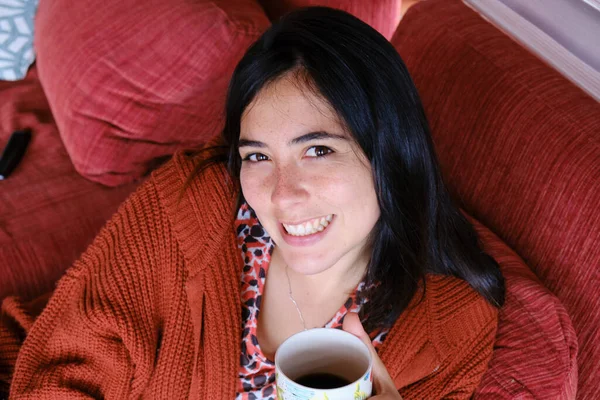 一个西班牙女人坐在沙发上喝咖啡的俯拍照片 — 图库照片