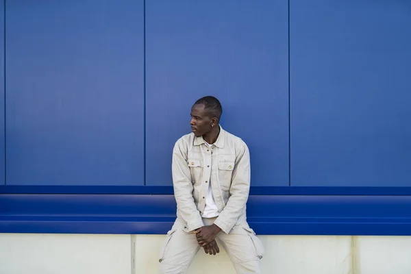 青い壁の前に立っている黒人の若い男性のクローズアップショット — ストック写真