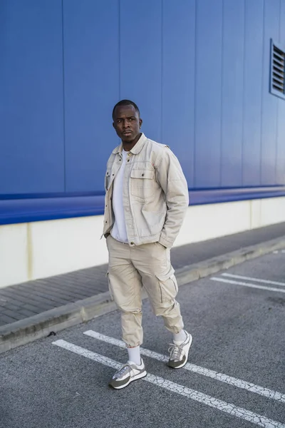 青い壁の前に立っている黒人の若い男性の垂直ショット — ストック写真