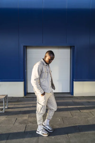 青と白の壁の前に屋外に立つ若い黒人男性の垂直ショット — ストック写真
