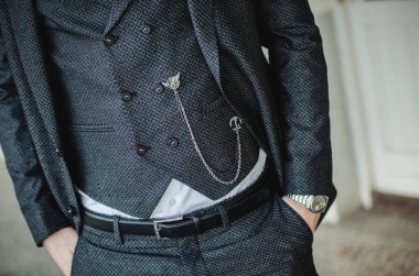A torso of a handsome male wearing a stylish dark gray 3-piece suit; a chain hanging on the waistcoat clipart