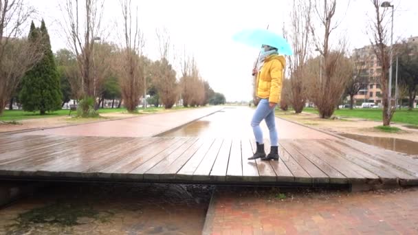 一位年轻的西班牙女子 带着雨伞在公园里慢吞吞地走着 雨天戴着面具 — 图库视频影像