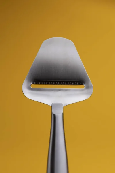 Dimmed stylish color palette around reflective stainless steel cheese slicer.