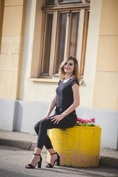 Attractive Caucasian Woman Sitting Yellow Concrete Surface Pink Flowers Park — Stock Photo, Image