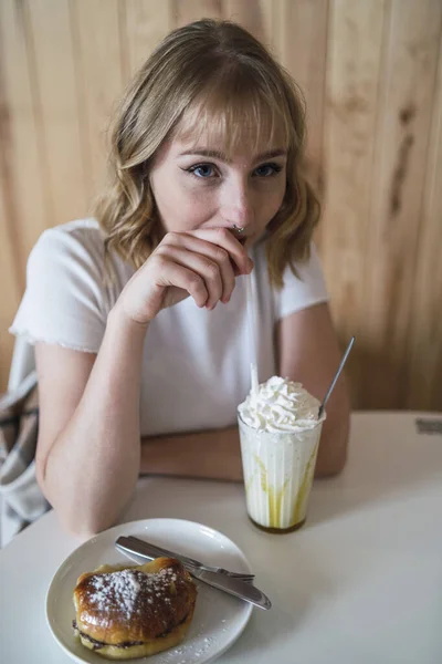 一个年轻漂亮的女人喝着奶昔 吃着甜点 — 图库照片